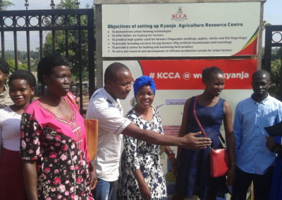 AYWD women with Henry in front of Kyanja Agricultural Resource Center sign