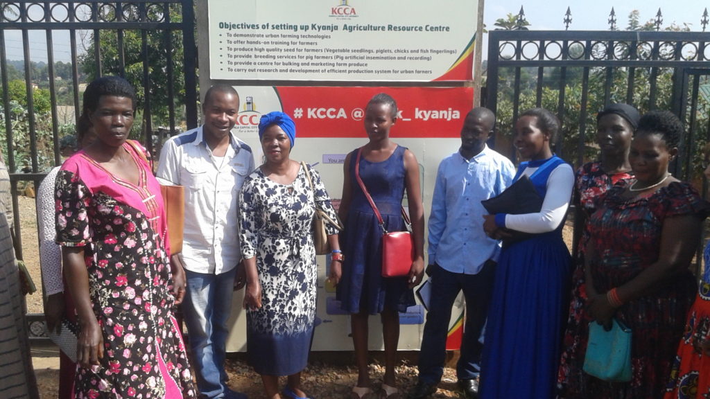 Henry, Ruth and members of AYWD at Kyanja Agricultural Resource Center - in front of sign